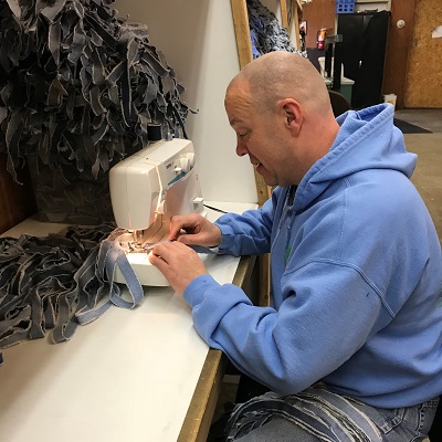 An employee concentrates on sewing fabric strips together to make STEP rugs.